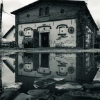 Altes Backsteingebaeude mit Spiegelung in einer Pfütze